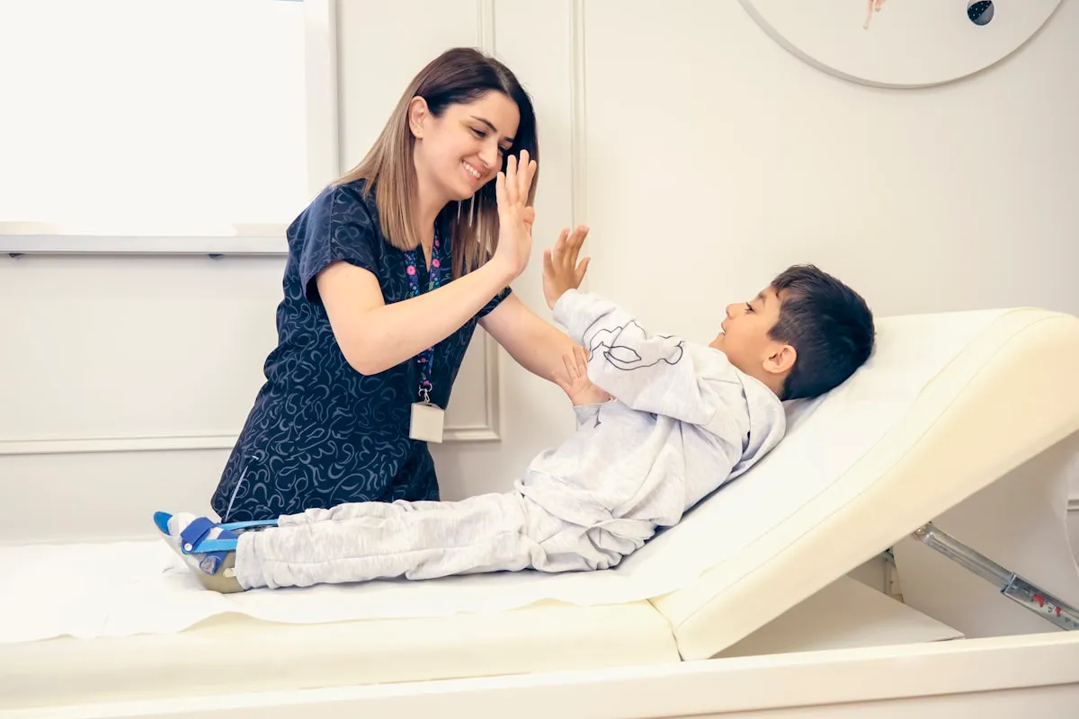 A nurse giving a young patient a high five on the exam table
